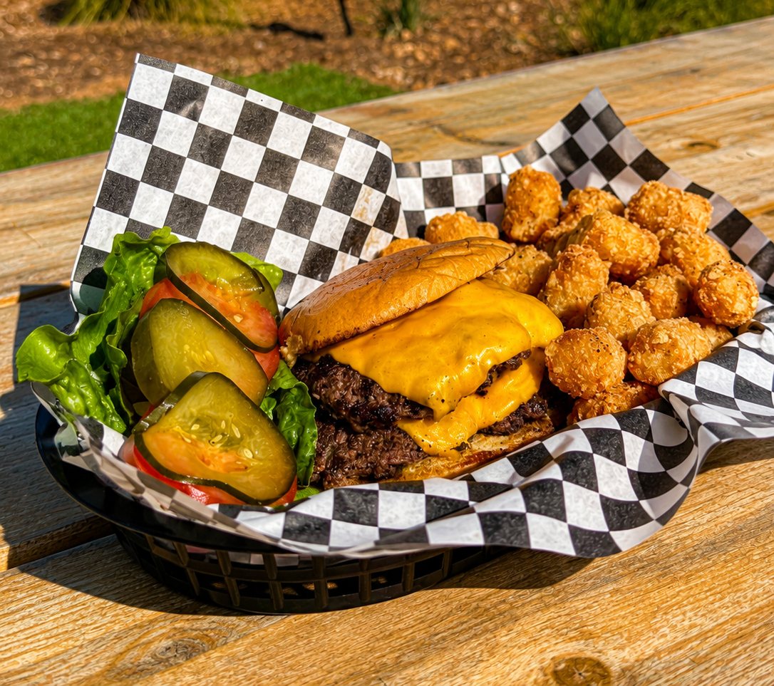 A Yachties O.G. smash burger with melted American cheese, lettuce, tomato and house-made pickles, served with Yacht Tots