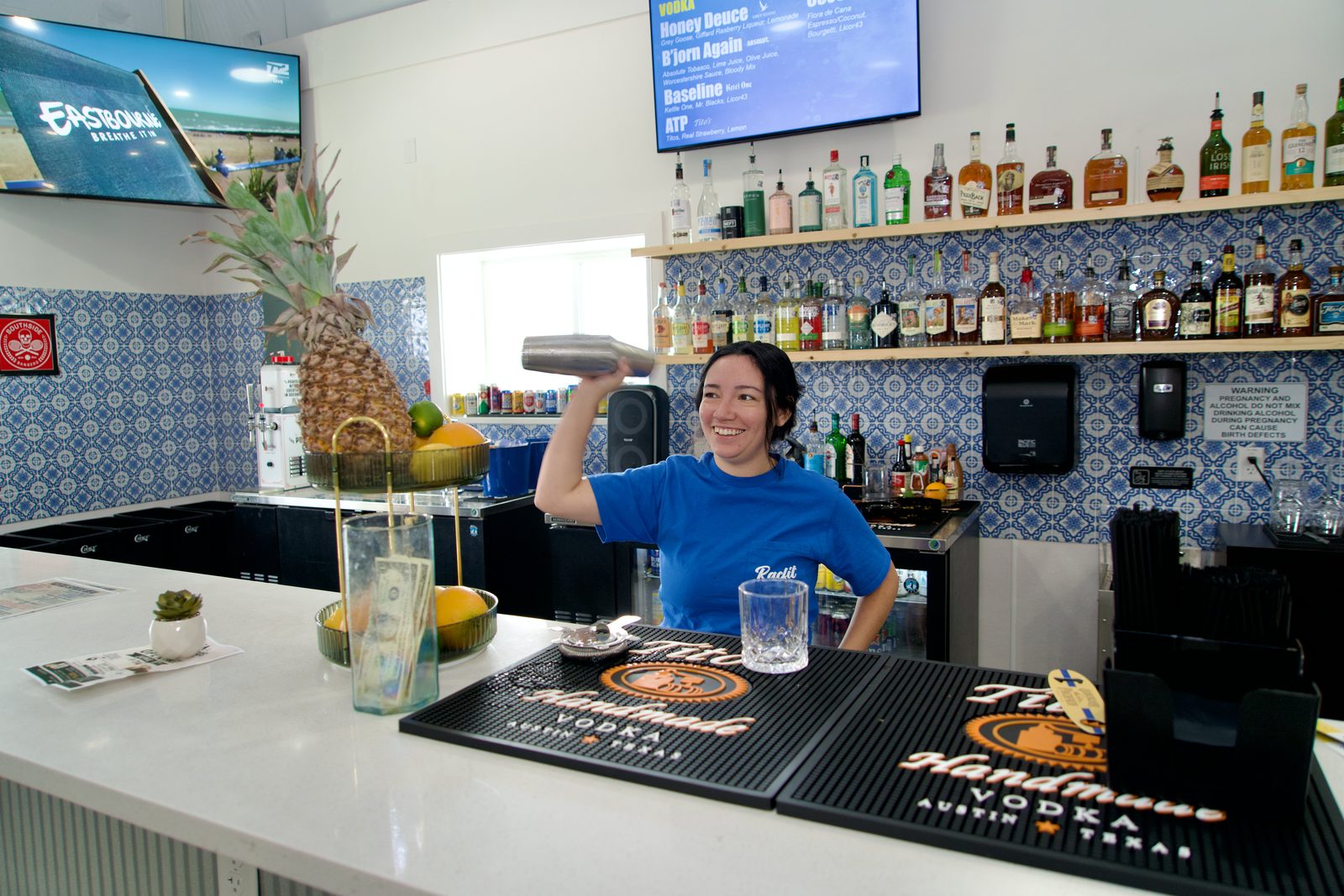 A bartender shaking a cocktail behind the Courtside Cantina bar